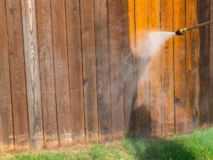 Spring Pressure Washing Checklist for Kitsap County Homes 2 Pressure washer cleaning a weathered wooden fence